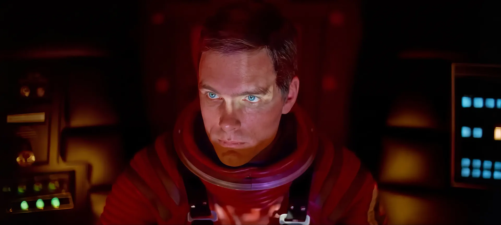 Dave Bowman in a red spacesuit, looking up from the pod.
