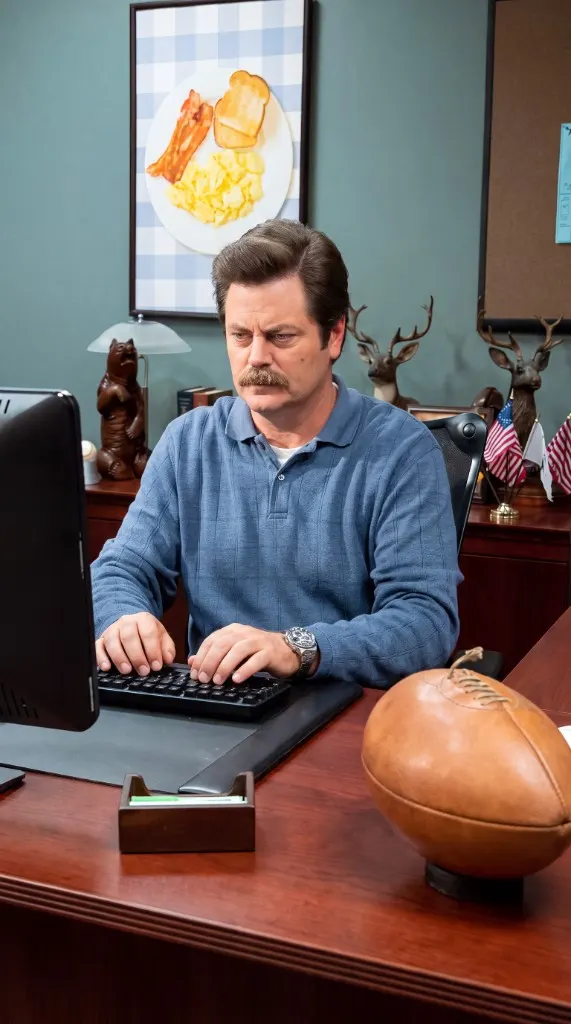 Ron Swanson at his desk, hands on the keyboard.